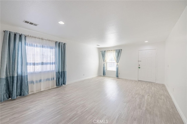 unfurnished room featuring recessed lighting, visible vents, light wood-style flooring, a textured ceiling, and baseboards