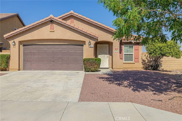 view of front of property with stucco siding, fence, a garage, driveway, and a tiled roof