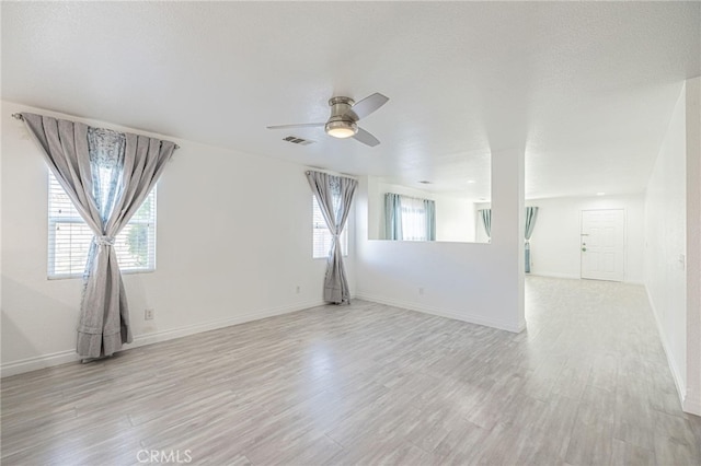 unfurnished room with ceiling fan, baseboards, visible vents, and light wood-style floors