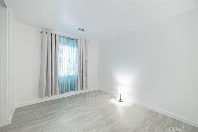 spare room with visible vents, baseboards, and wood finished floors