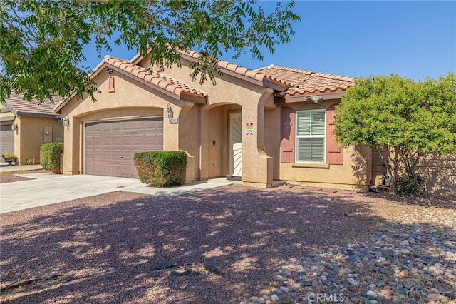 view of front of home with concrete driveway, an attached garage, a tiled roof, and stucco siding