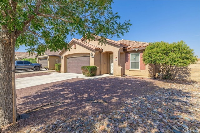 view of front of home with an attached garage, a tile roof, concrete driveway, and stucco siding