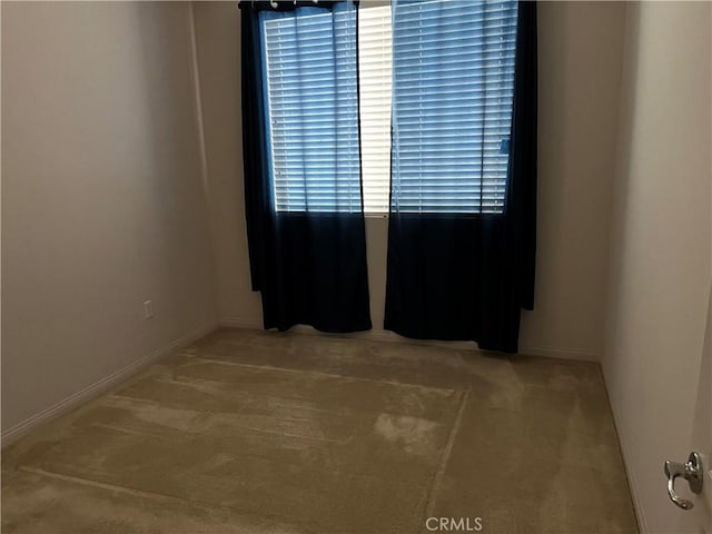 carpeted spare room featuring baseboards