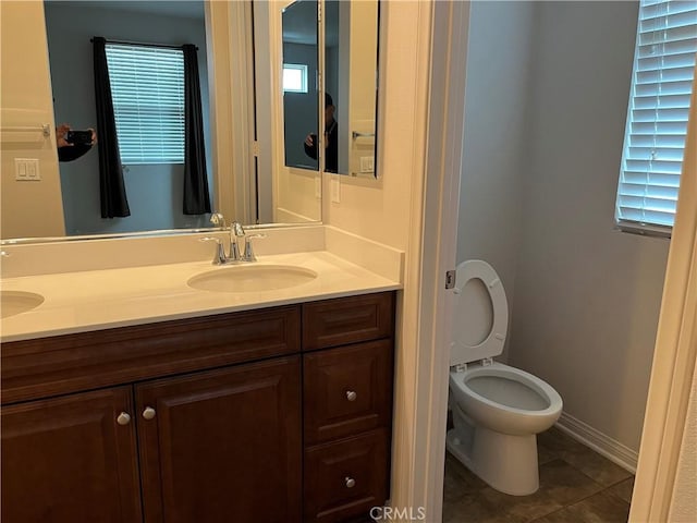 bathroom featuring double vanity, toilet, a sink, and tile patterned floors