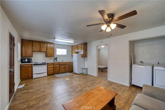 kitchen with brown cabinets, light countertops, wood finished floors, washer and dryer, and white appliances