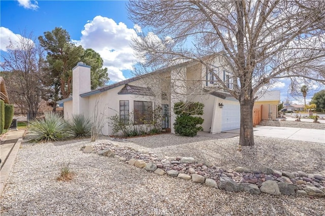 view of front of home featuring a garage, a chimney, concrete driveway, and stucco siding