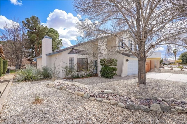 view of front facade with driveway, an attached garage, a chimney, and stucco siding