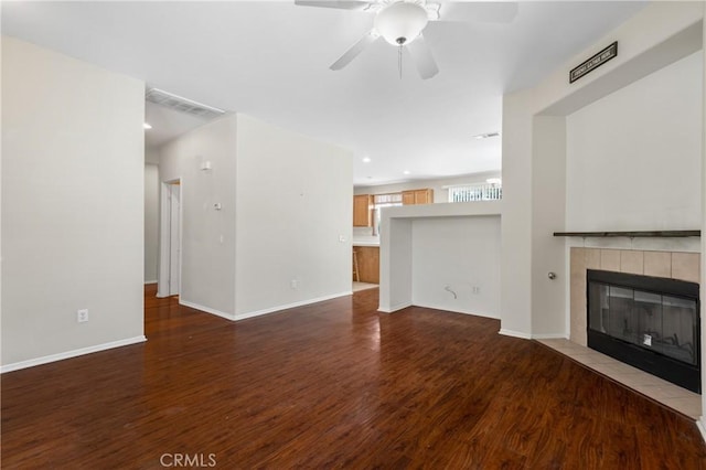 unfurnished living room with baseboards, a fireplace, a ceiling fan, and wood finished floors