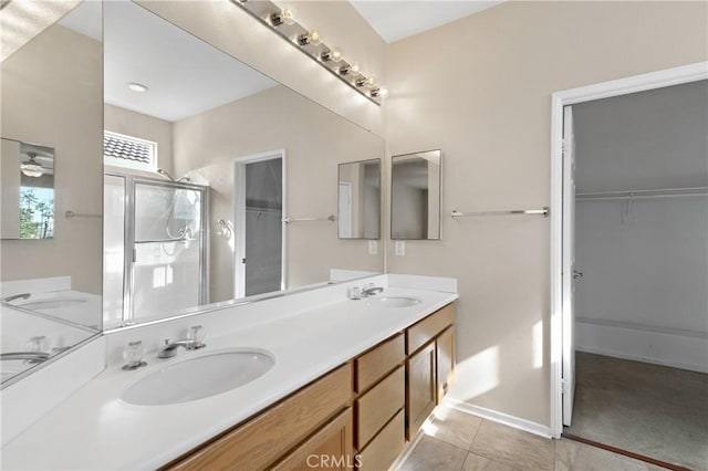 bathroom with double vanity, tile patterned flooring, a shower stall, and a sink