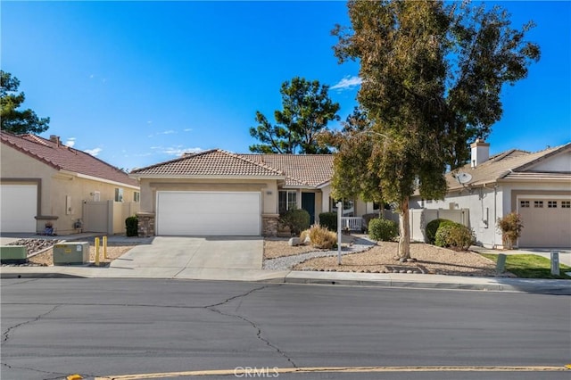 view of front of property with concrete driveway, stone siding, a tile roof, an attached garage, and fence