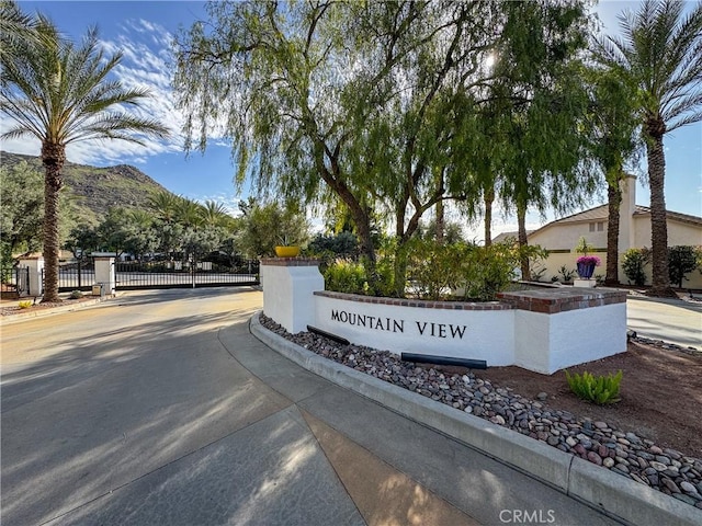 community / neighborhood sign featuring a gate, fence, and a mountain view