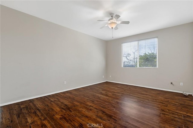 unfurnished room featuring dark wood-style flooring, a ceiling fan, and baseboards