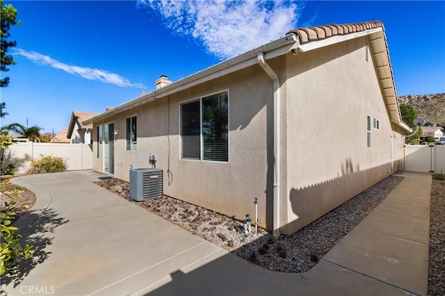 view of home's exterior with central AC, a patio area, fence, and stucco siding