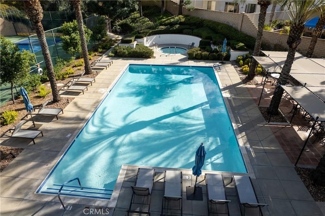 pool featuring a community hot tub, a patio, and fence