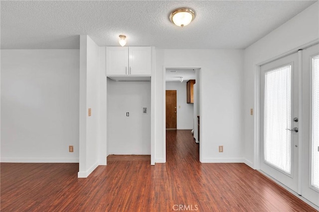 interior space featuring dark wood-style flooring, a textured ceiling, and baseboards