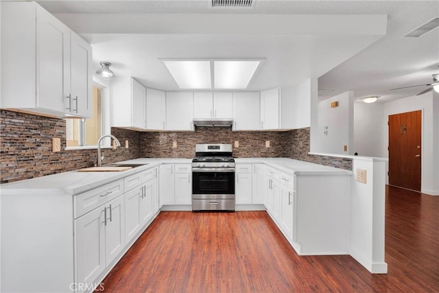 kitchen featuring visible vents, gas stove, a sink, wood finished floors, and under cabinet range hood