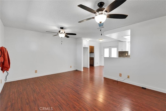 unfurnished living room with baseboards, visible vents, ceiling fan, wood finished floors, and a textured ceiling