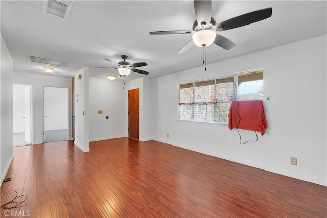 spare room with a textured ceiling, wood finished floors, and visible vents