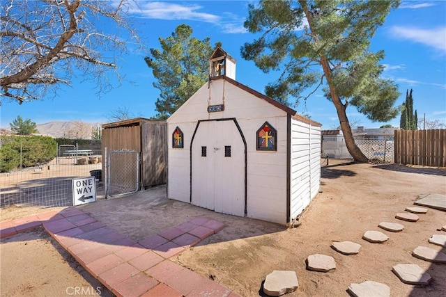 view of shed with a mountain view, fence, and a gate