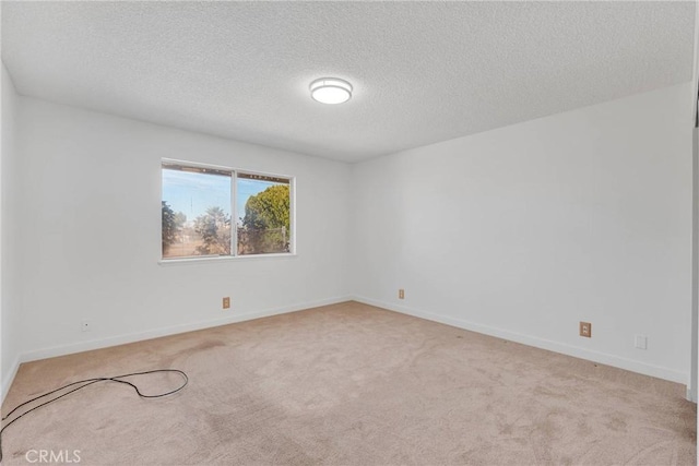 spare room with light colored carpet, a textured ceiling, and baseboards