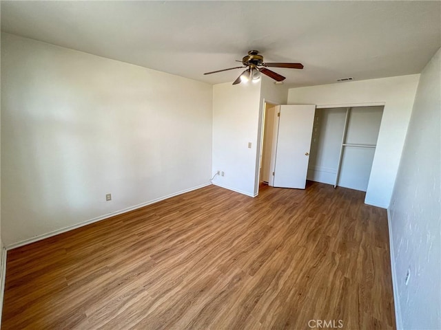 unfurnished bedroom featuring a closet, visible vents, ceiling fan, wood finished floors, and baseboards