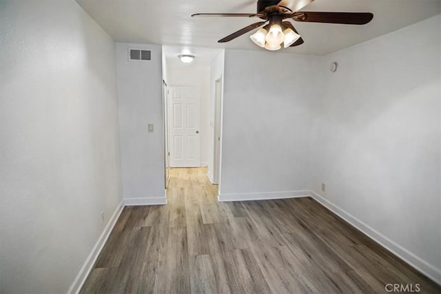 spare room featuring ceiling fan, wood finished floors, visible vents, and baseboards