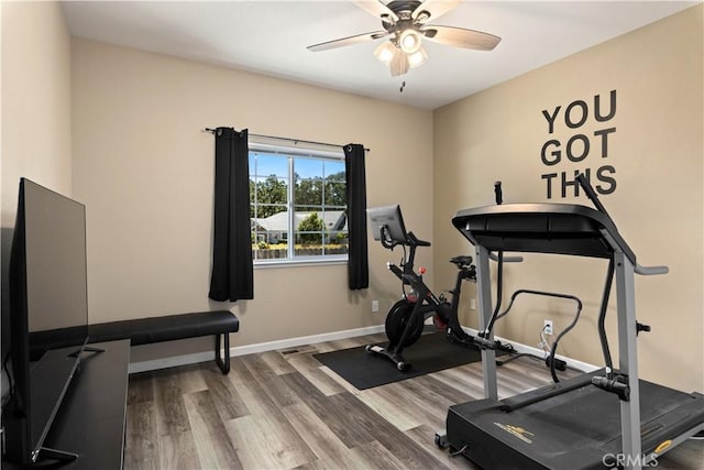 workout room with a ceiling fan, baseboards, and wood finished floors