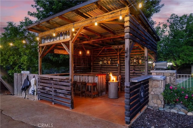 patio terrace at dusk featuring outdoor dry bar and area for grilling