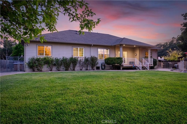 ranch-style home featuring fence and a lawn