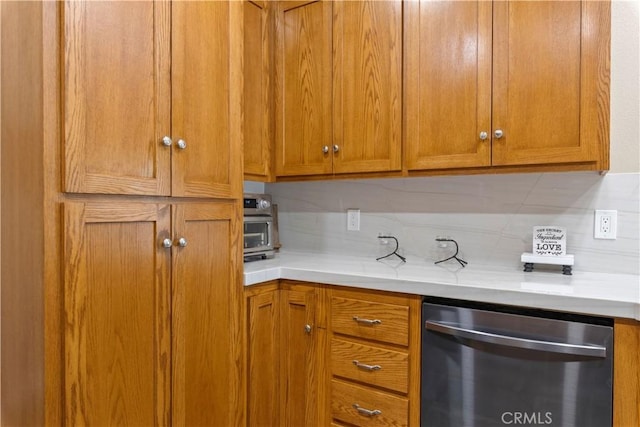 kitchen with dishwasher, light countertops, tasteful backsplash, and brown cabinets