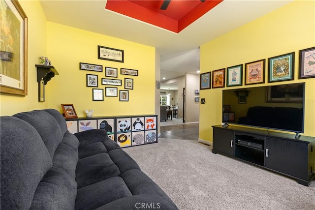 living area with carpet floors, baseboards, and a raised ceiling