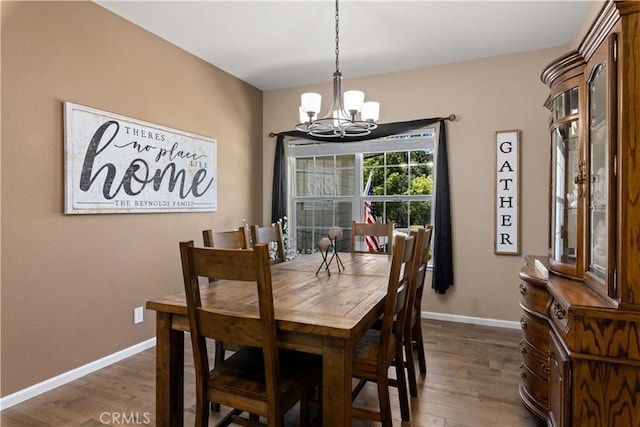 dining area with baseboards, an inviting chandelier, and wood finished floors