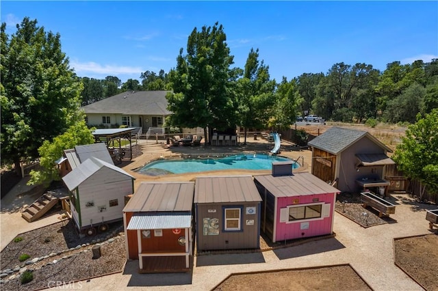 view of pool featuring a fenced in pool, a patio, fence, a water slide, and an outdoor structure