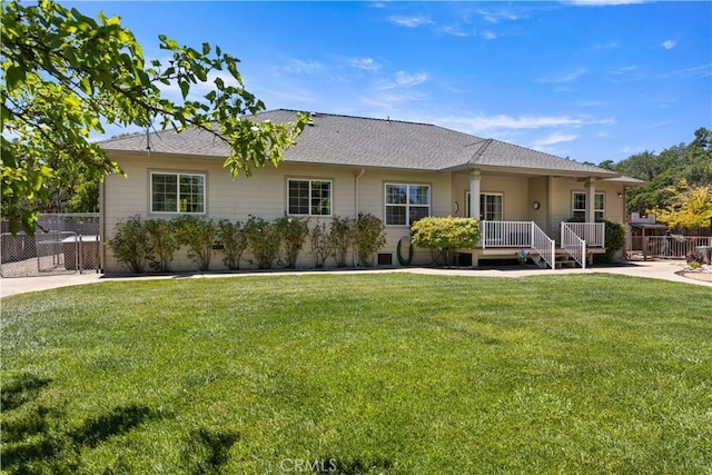 rear view of property featuring a lawn and fence