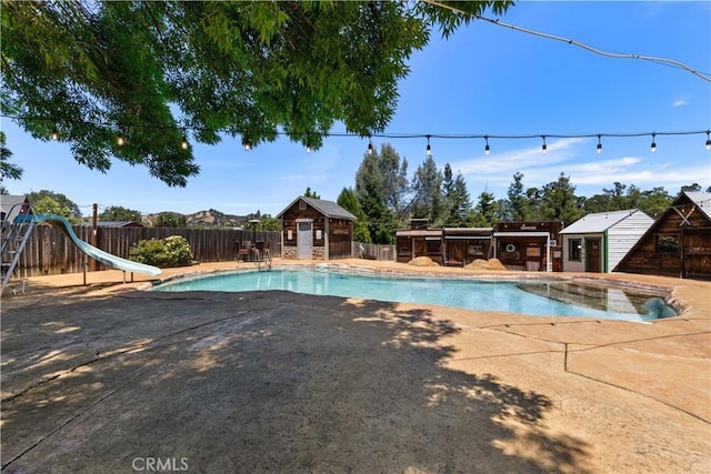 view of pool with a patio, a water slide, a fenced backyard, an outdoor structure, and a fenced in pool