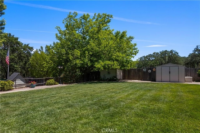 view of yard with a fenced backyard, an outdoor structure, and a storage shed