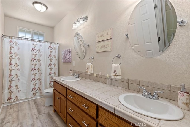 bathroom with wood finished floors, a sink, toilet, and a shower with curtain