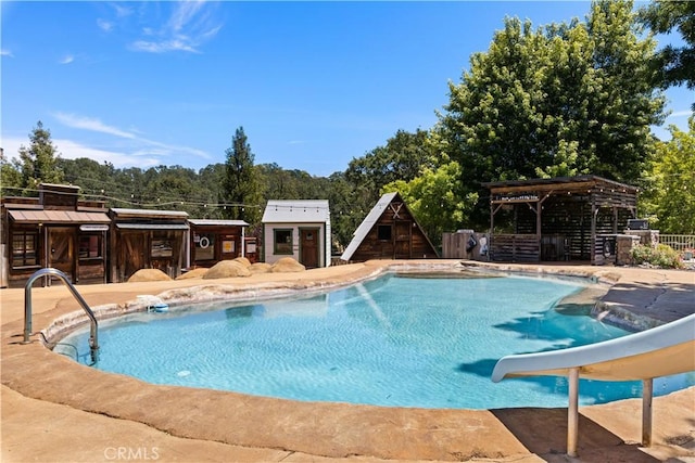 pool featuring a water slide and a patio