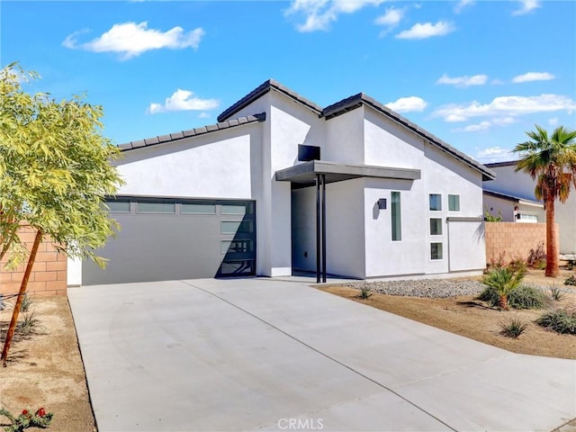 view of front of home featuring stucco siding, concrete driveway, an attached garage, and fence