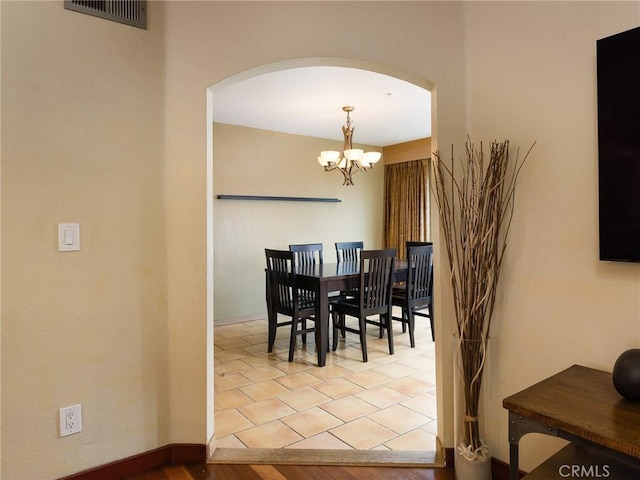 dining area with a chandelier, arched walkways, visible vents, and baseboards