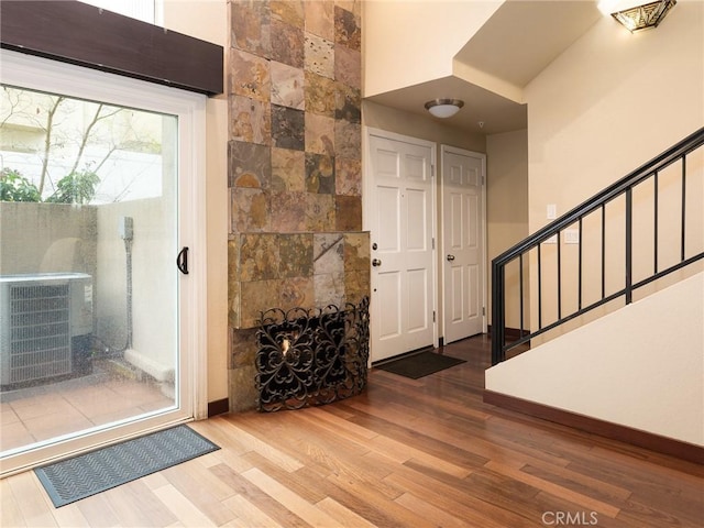 entrance foyer with stairway, a tiled fireplace, wood finished floors, and tile walls