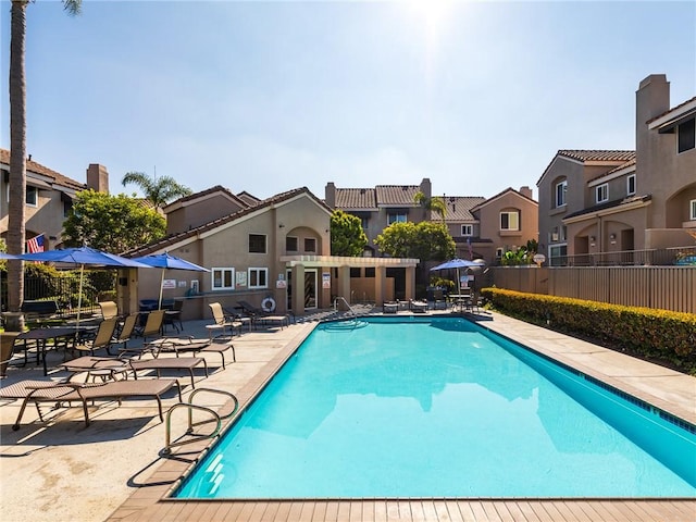 community pool with a patio area, a residential view, and fence