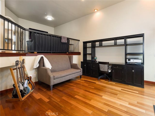 home office with light wood-style floors, built in desk, and baseboards