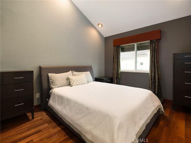 bedroom with vaulted ceiling and dark wood-style flooring