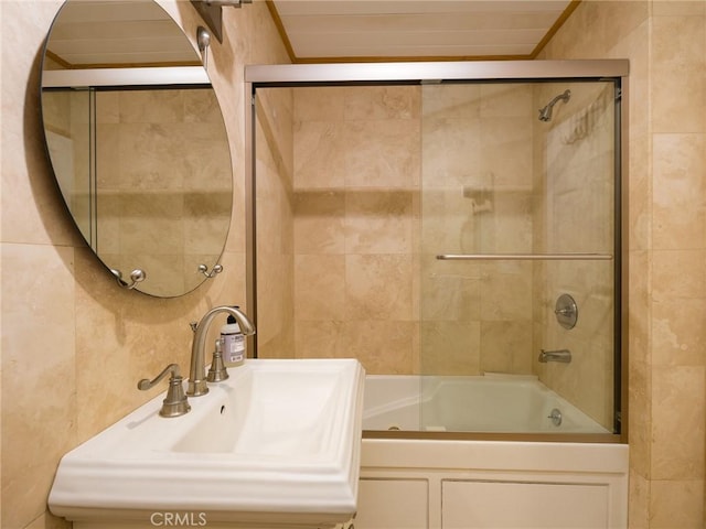 bathroom featuring enclosed tub / shower combo, a sink, and tile walls