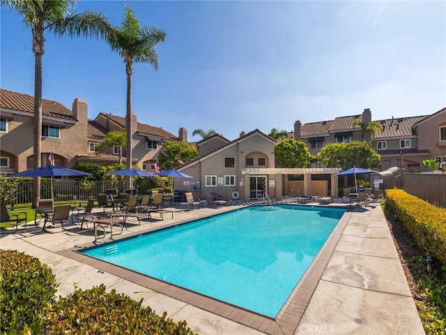 community pool featuring a residential view, fence, and a patio