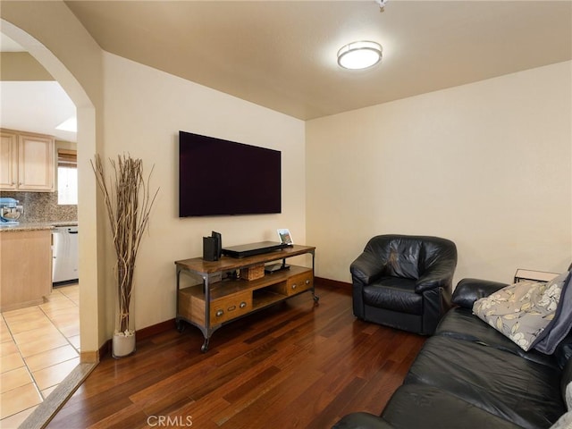 living room featuring arched walkways, baseboards, and light wood finished floors