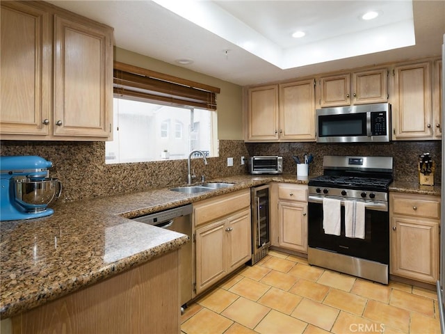 kitchen featuring light brown cabinets, beverage cooler, a sink, appliances with stainless steel finishes, and a raised ceiling