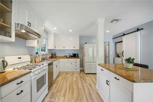 kitchen featuring visible vents, a barn door, white cabinets, white appliances, and under cabinet range hood