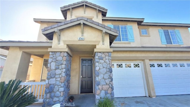 property entrance with stone siding, an attached garage, and stucco siding